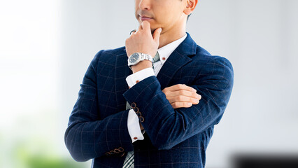 腕組みをして考えごとをする日本人男性ビジネスマン