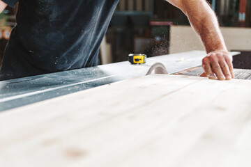 Carpenter cutting wooden plank using circular saw in workshop
