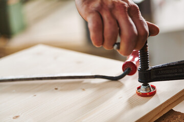 Carpenter using c clamp for woodworking project in workshop