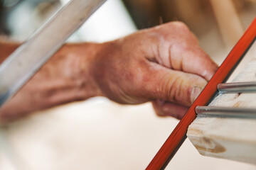 Carpenter working on wood plank using a file in his workshop