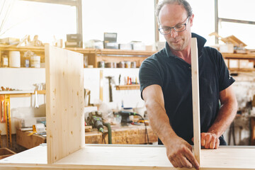Senior carpenter working on a wooden furniture piece in his work