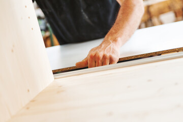 Carpenter assembling wooden furniture in workshop