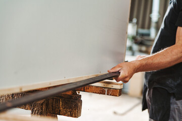 Carpenter using crowbar repairing wooden panel in workshop