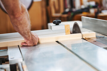 Carpenter cutting wood plank using circular saw