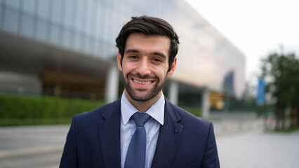 Portrait of smiling business man looking at camera while standing at building. Closeup of successful man smiling at camera while wearing business suit. Happy manager look at camera. Exultant.