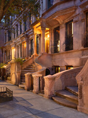 Evening view of iconic brownstones with stoop steps in New York City's Harlem, Manhattan. This row...