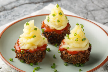 Meat muffins topped with tomato sauce and mashed potatoes close-up in a plate on the table. Idea for a buffet table. Horizontal