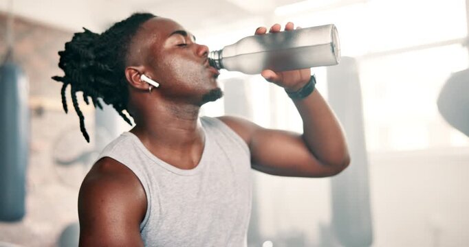 Black man, drinking water and fitness in gym for exercise break and health, boxing energy or training challenge. Thirsty sports person or boxer listening to music and bottle for nutrition in workout