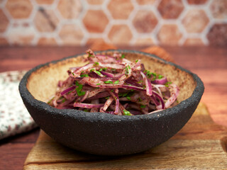 A bowl of sumac onions, a popular Turkish side dish, known for its tangy and fresh flavor. The onions are thinly sliced and mixed with parsley, dressed with sumac spice, giving them a distinctive redd