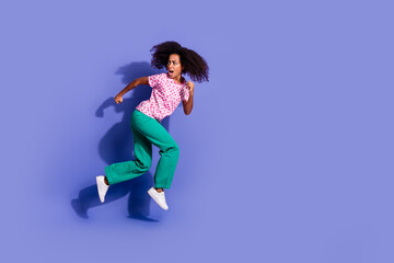 Full size photo of young girl running turn around look scared empty space wear trendy pink outfit isolated on purple color background