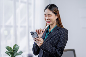 Young busy happy business asian woman employee, young female corporate executive holding digital phone standing at work. 