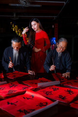 Vietnamese girl with red Ao Dai dress and old scholars writing calligraphy at lunar new year....
