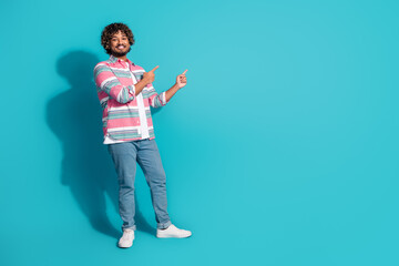 Photo of cheerful handsome man wear stylish striped clothes presents empty space isolated on cyan color background