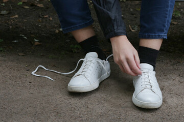 The process of tying shoelaces on sneakers.