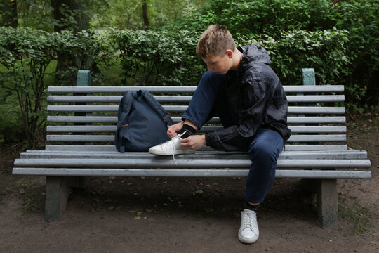 A teenage boy ties his shoelaces. - Powered by Adobe
