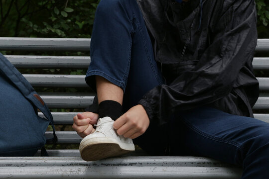 boy on a bench tying his shoelaces. - Powered by Adobe
