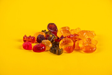Fruit flavored worm shape, jelly candies. Isolated on yellow background.