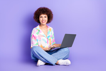 Full body photo of attractive young woman sit floor hold netbook dressed stylish colorful clothes isolated on violet color background