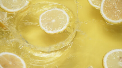 Close up of fresh lemon slices water splashing on separated yellow background. Macrography of...