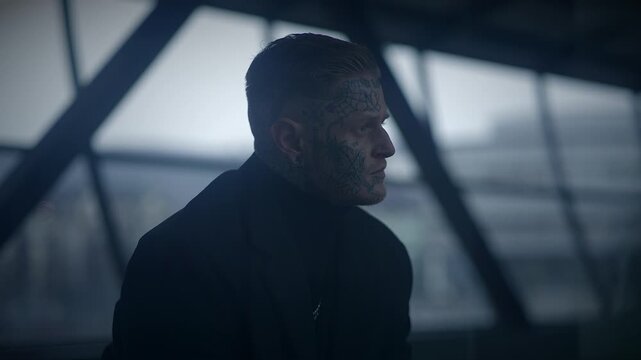 A man with facial tattoos in urban setting with dramatic lighting and gritty atmosphere