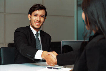 Business people agreement concept. Businessman and Asian businesswoman do handshake in the office. uds