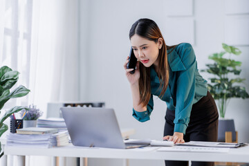 Obraz premium Cheerful business Asian woman employee making telephone call share good news about project work in office workplace, business financing accounting banking concept.