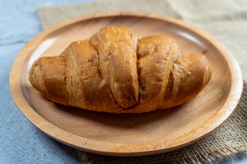 a croissant in wooden plate on top gunny sack