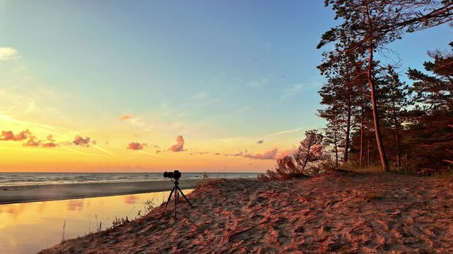 Camera on tripod on a beautiful beach during sunset at Irbes ieteka with copy space