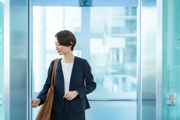 エレベーターのボタンを押す女性 © ponta1414