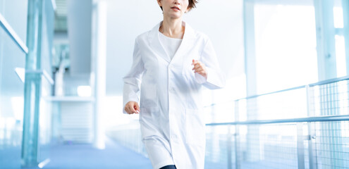 病院を走る白衣を着た女性