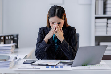 Portrait of tired  business asian woman sitting at a work. documents tax laptop computer in office. Sad, unhappy, Worried, Depression, or overworked, failure employee life stress concept	