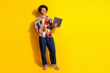 Full body portrait of nice funky young man laptop empty space wear shirt isolated on vibrant yellow color background