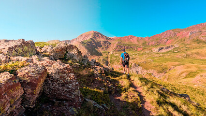 Fototapeta premium Discovering the Pyrenees: young man ascending Arroyetas Peak, surrounded by the beauty of the Ibón de Anayet, Anayet Peak and the majestic Midi d'Ossau 