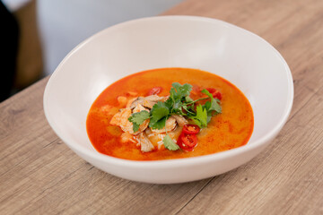 close up in a restaurant on light table a white plate with Japanese udon soup with red soup with...