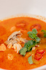 top shot close up in a restaurant on light table a white plate with Japanese udon soup with red...