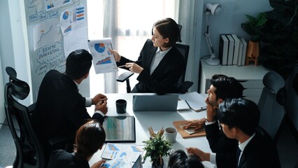 Top view of smart manager compare chart between board and paper while planning startup project with group of diverse team at business meeting. Team brainstorming and working together. Directorate.