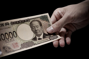 日本の新紙幣。一万円札を1枚持っている手のネガティブなイメージ