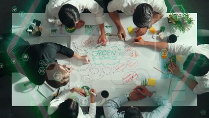 Top view of business team discussing about using clean energy and sustainable investment at meeting table with wind mill, document with environmental graph and holographic of eco power. Alimentation.