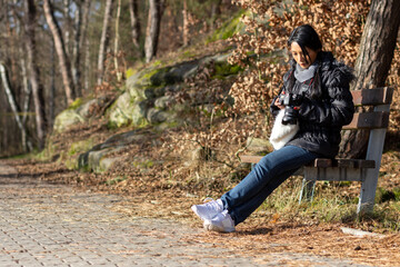 Fototapeta premium A young woman with a camera sitting on a bench