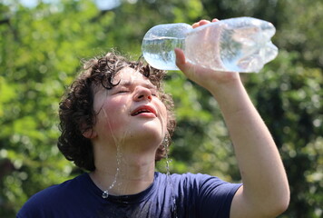 A guy pours water on himself in the heat.