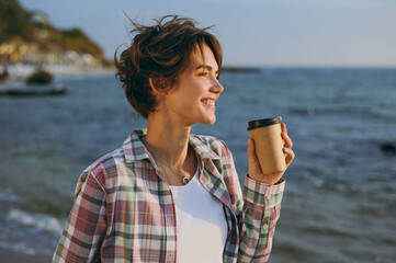 Close up young woman wear shirt casual clothes hold takeaway delivery craft paper brown cup coffee...