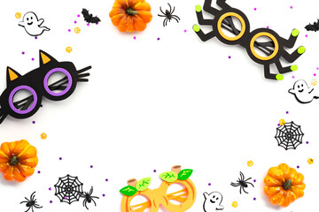 Happy Halloween holiday concept. Frame made of pumpkins, spooky glasses, spiders, ghosts, decorations, confetti on white background