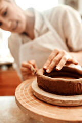 Hands, clay and wheel for pottery with craft, tools or skills at small business in workshop. Woman,...