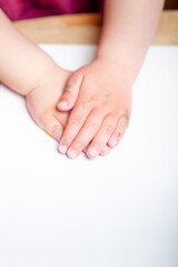Hands of an unrecognizable kid resting on a white canvas before starting to paint his artwork.
