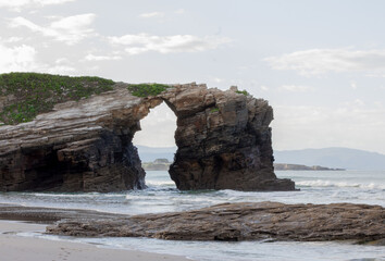 Rocky coastal arch formation, dramatic natural landscape scenery, geological wonder. Cathedral Beach, Lugo, Spain