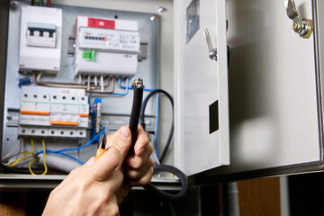 Removing PVC sheath of an electrical cable with retractable utility knife, against background of an...