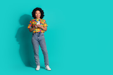 Full length photo of cheerful pretty lady dressed vintage t-shirt typing modern gadget empty space isolated blue color background