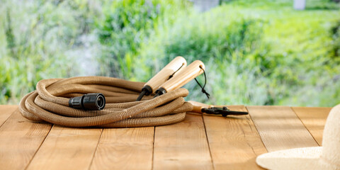 Wooden board table top and panoramic landscape of summer garden and garden tools. Summer flowers and trees  background and montage objects display.