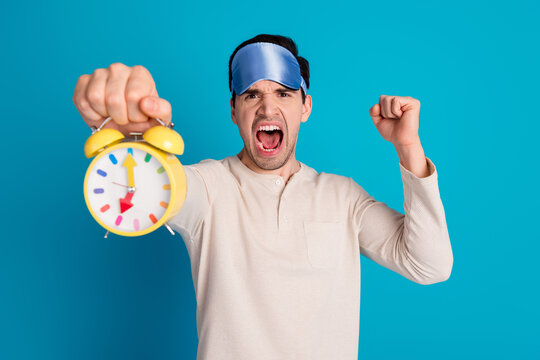 Photo of nice young man hold alarm shout wear pajama isolated on blue color background