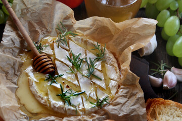Baked camembert cheese with rosemary, garlic and honey on baking paper